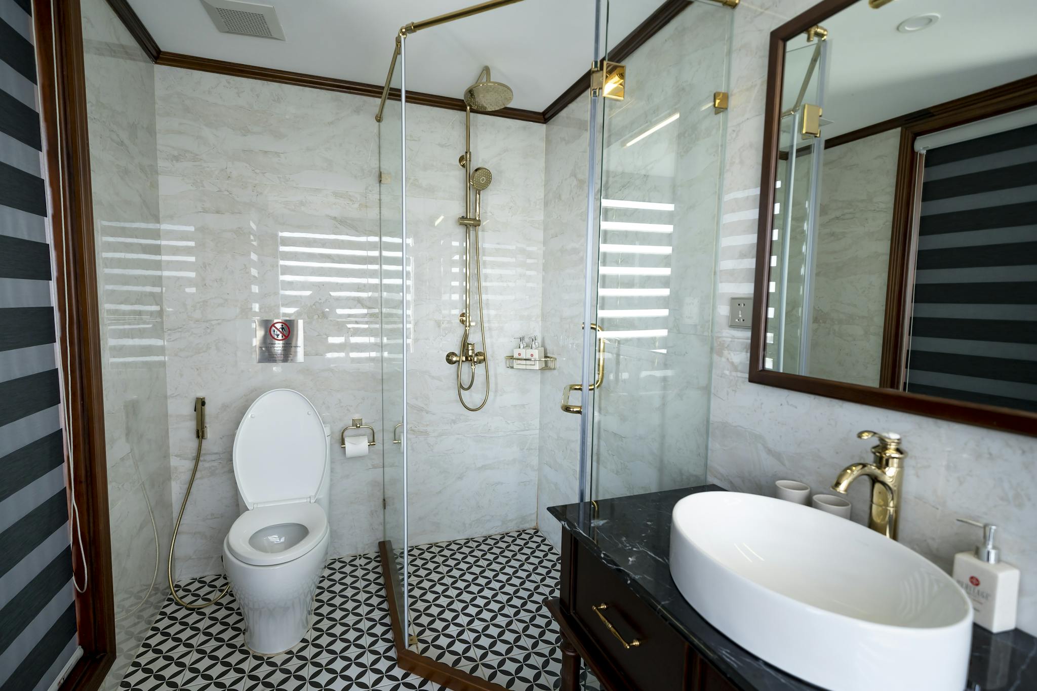 Elegant bathroom featuring glass shower, white sink, and gold fixtures.